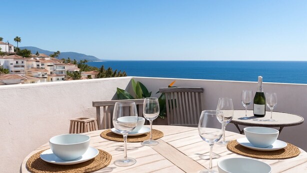 A table set for dining with a view of the sea and buildings in the background. - Lavender House - Hacienda 37 by Casasol (Nerja)