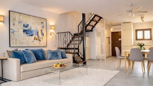 Un salon moderne avec un canapé blanc, une table basse en verre et un escalier.