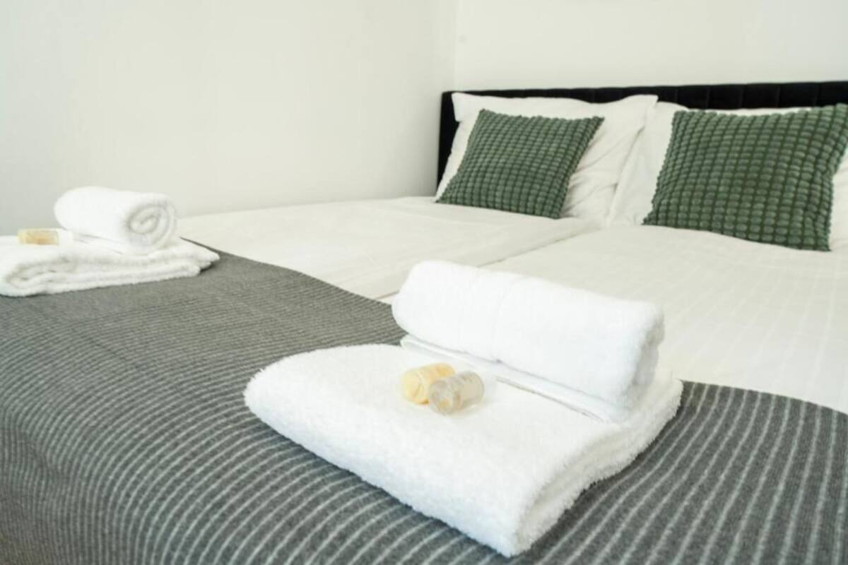 A hotel room with a neatly made bed, green striped bedding, and two green pillows.