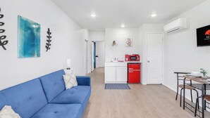 Een moderne woonkamer met een blauwe bank, een keuken met een rode koelkast, en een eettafel met stoelen.