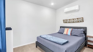 Een slaapkamer met een bed, een airconditioner en een decoratief wandobject.