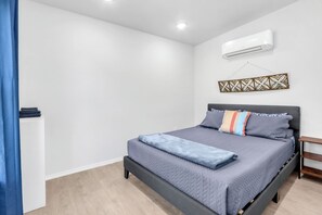 A bedroom with a bed, an air conditioner, and a decorative wall piece. - Private Hot Tub Apartment | Hill Country Getaway Near Canyon Lake (Canyon Lake)
