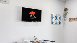 Een eetgedeelte met een tafel voor twee personen, een televisie waarop het logo van Hill Country Premier Lodging staat, en een blauw abstract schilderij aan de muur.