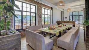 A restaurant with large windows, cushioned seating, and potted plants. - Olive Ala-Archa Hotel & SPA (Kashka-Suu)