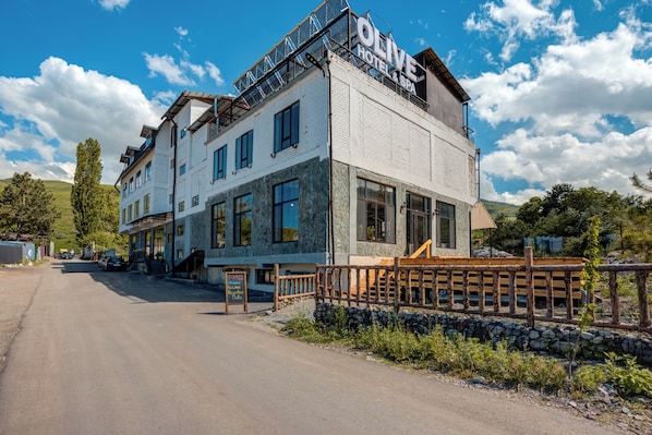 Een hotel met een gevel van steen, meerdere ramen en een bord waarop 'OLIVE HOTEL & SPA' staat.