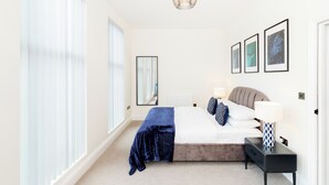 Ein Schlafzimmer mit einem Bett, Nachttischen, einem Spiegel und gerahmten Bildern an der Wand.