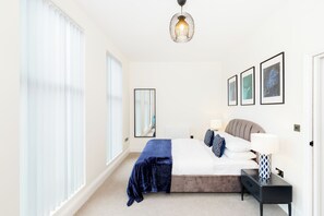 A bedroom with a bed, bedside tables, a mirror, and framed pictures on the wall. - Modern 4-Bedroom Townhouse with Parking in Birmingham England, Jewellery Quarter (Birmingham)