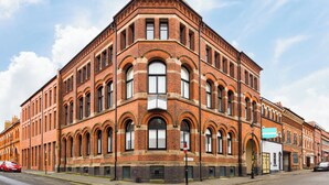 Ein großes, historisches Backsteingebäude mit Rundbogenfenstern und einem markanten Eckturm.