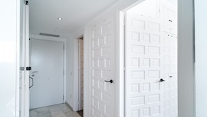 A hallway with white doors, a tiled floor, and a ceiling light. - Verano Azul 96 Casa Monica by Casasol (Nerja)