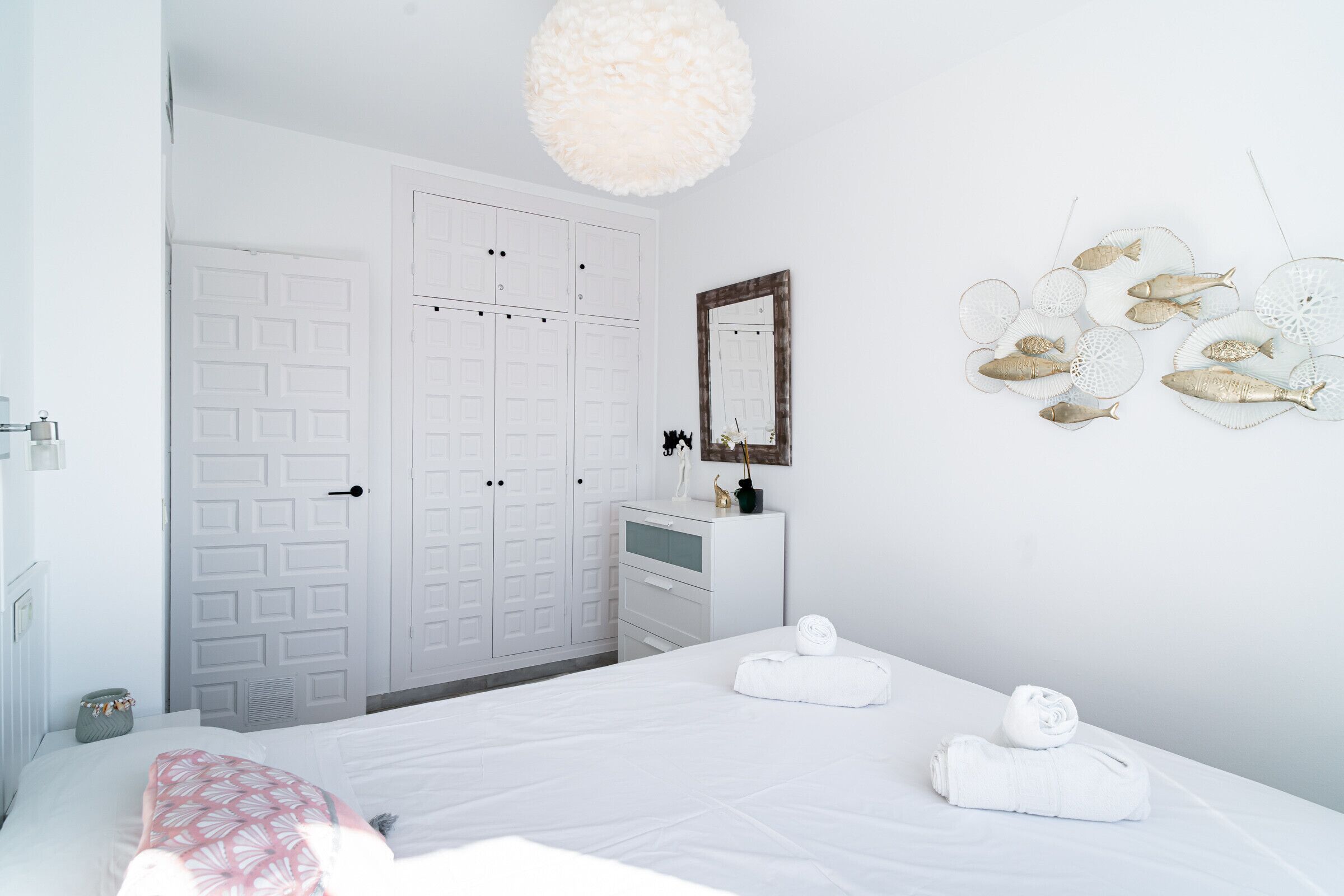 Habitación de hotel con cama, cómoda, espejo y decoración de peces en la pared.