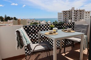 A balcony with a table, chairs, and a view of the sea and buildings. - Verano Azul 96 Casa Monica by Casasol (Nerja)