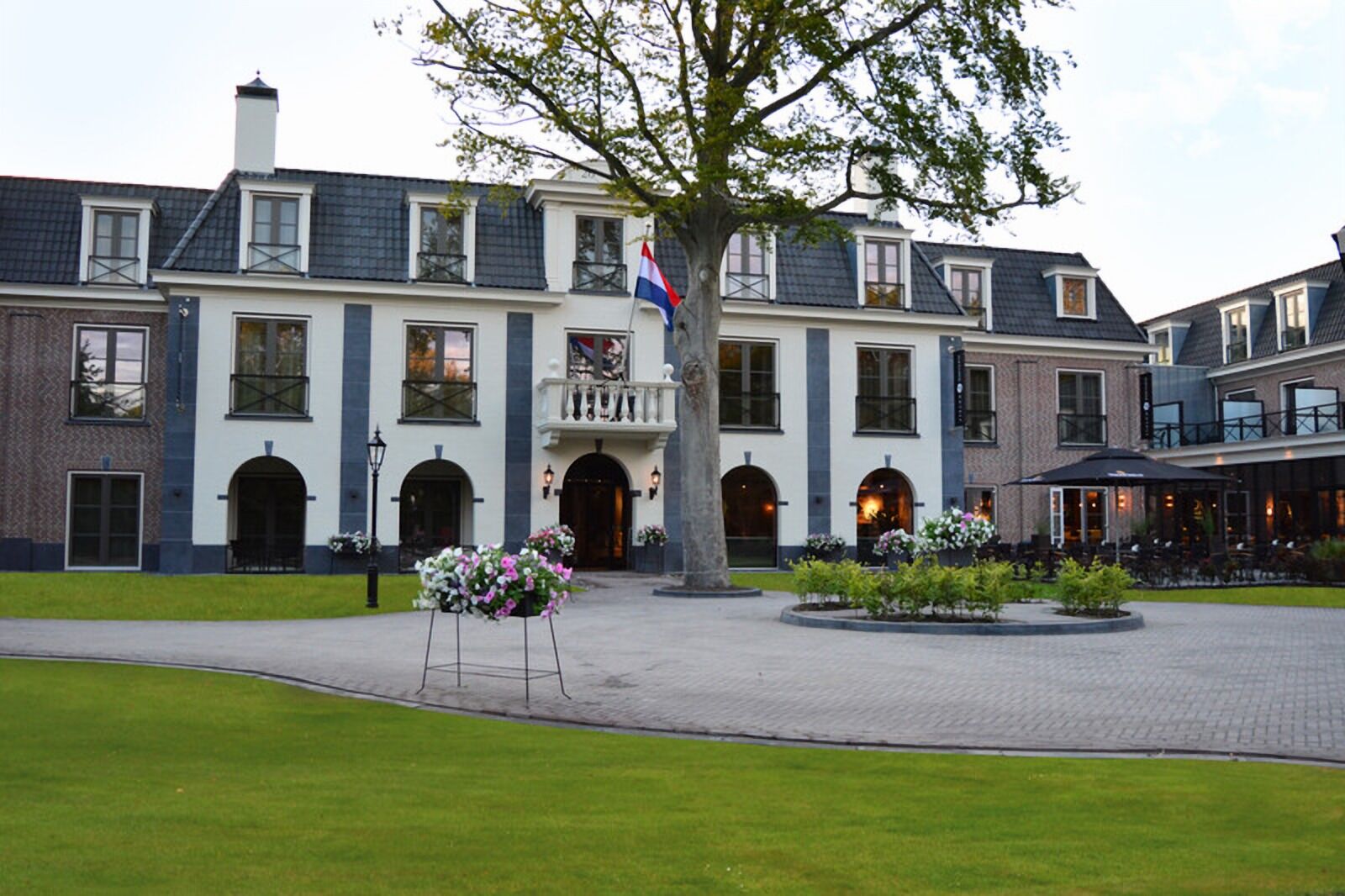 A large, historic building with a central entrance, multiple windows, and a flag.