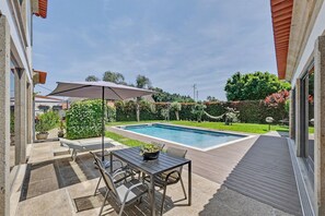 Une terrasse avec une piscine, du mobilier d’extérieur et une vue sur la piscine.