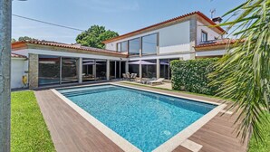 Ein modernes Haus mit Swimmingpool, großen Fenstern und einer Terrassenfläche.