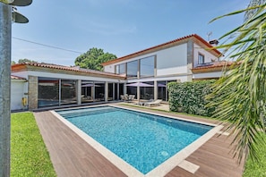 Uma casa moderna com piscina, janelas amplas e área de varanda.