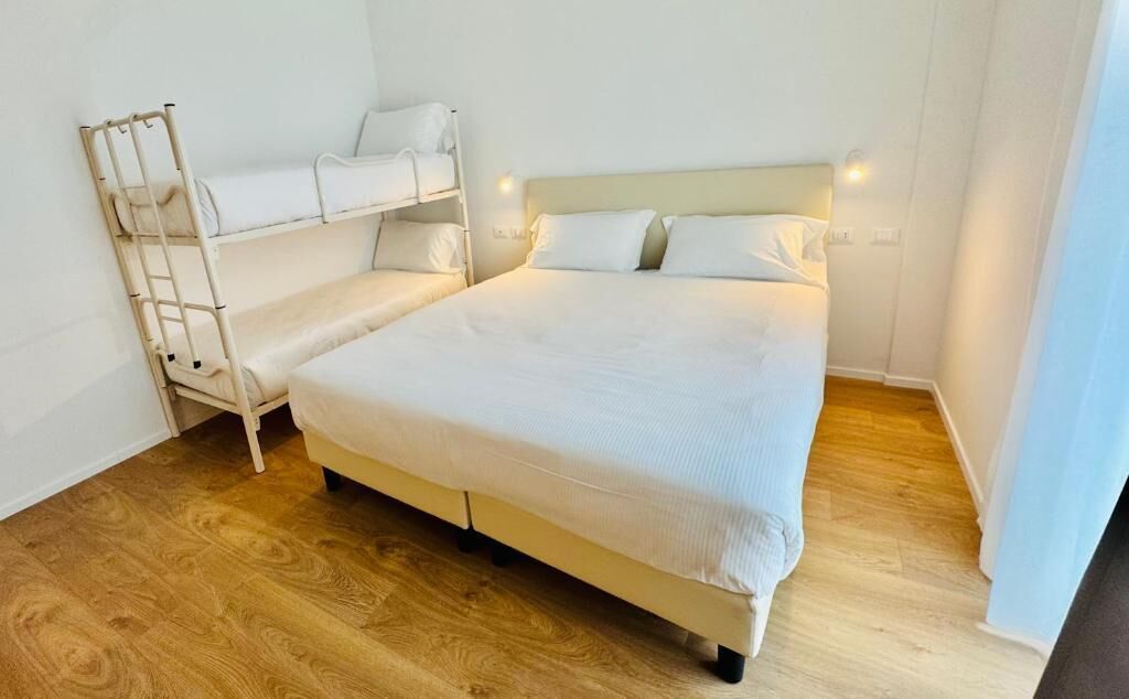 A room with a single bed, a bunk bed, and a wooden floor.