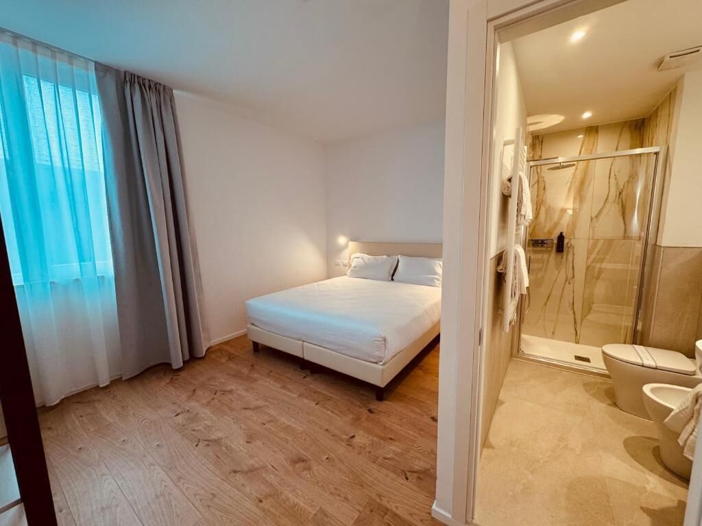 Un dormitorio con cama, zona de ducha con puerta de cristal y un inodoro.