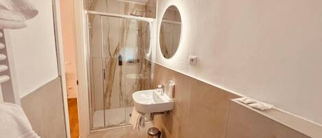 A modern bathroom with a glass shower enclosure, a sink, and a mirror.