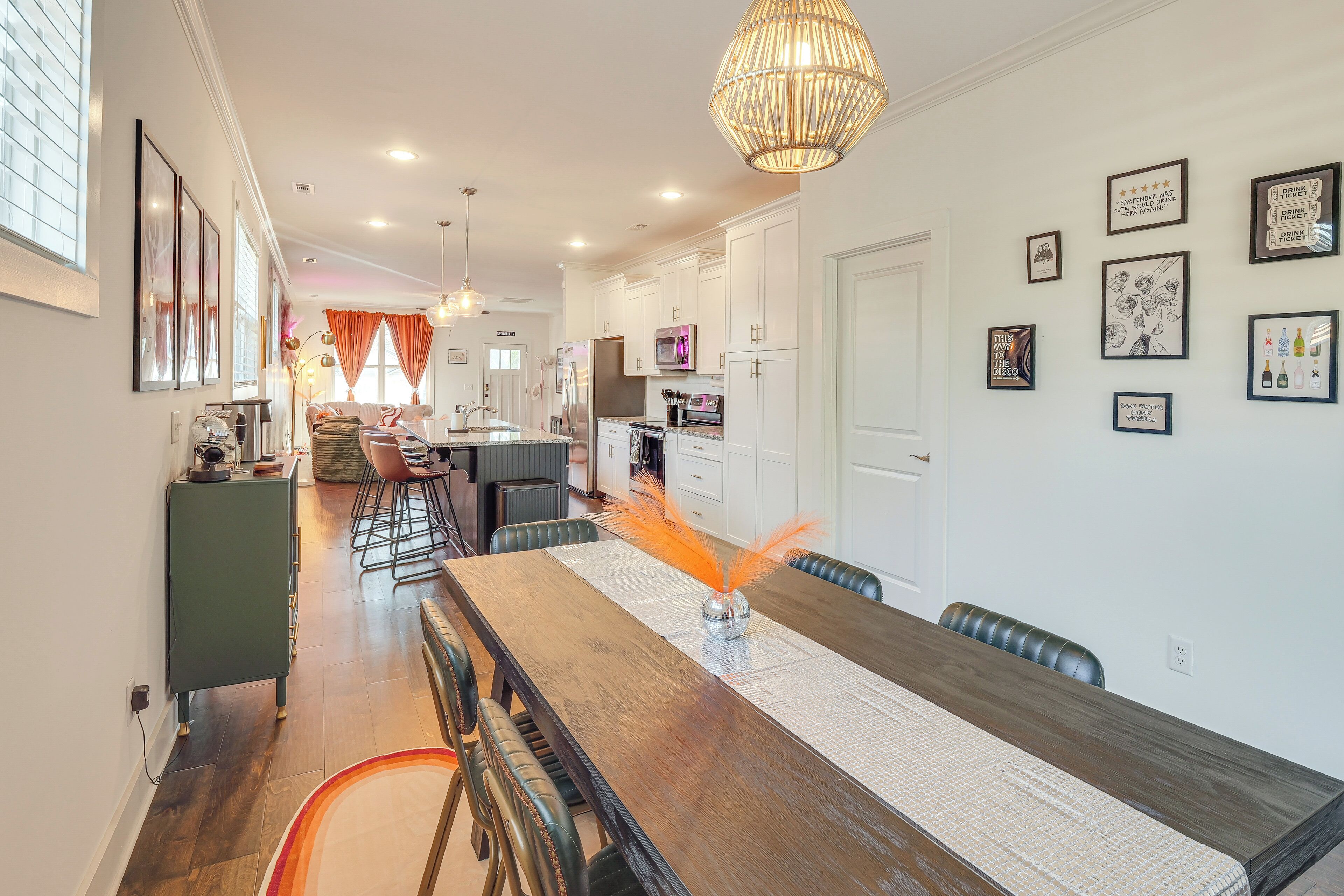A modern kitchen with white cabinets, stainless steel appliances, and a dining area with a long wooden table and chairs.