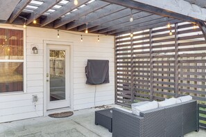 Eine überdachte Terrasse mit einem Rattangeflechtsessel, Lichterketten und einem Holzzaun.