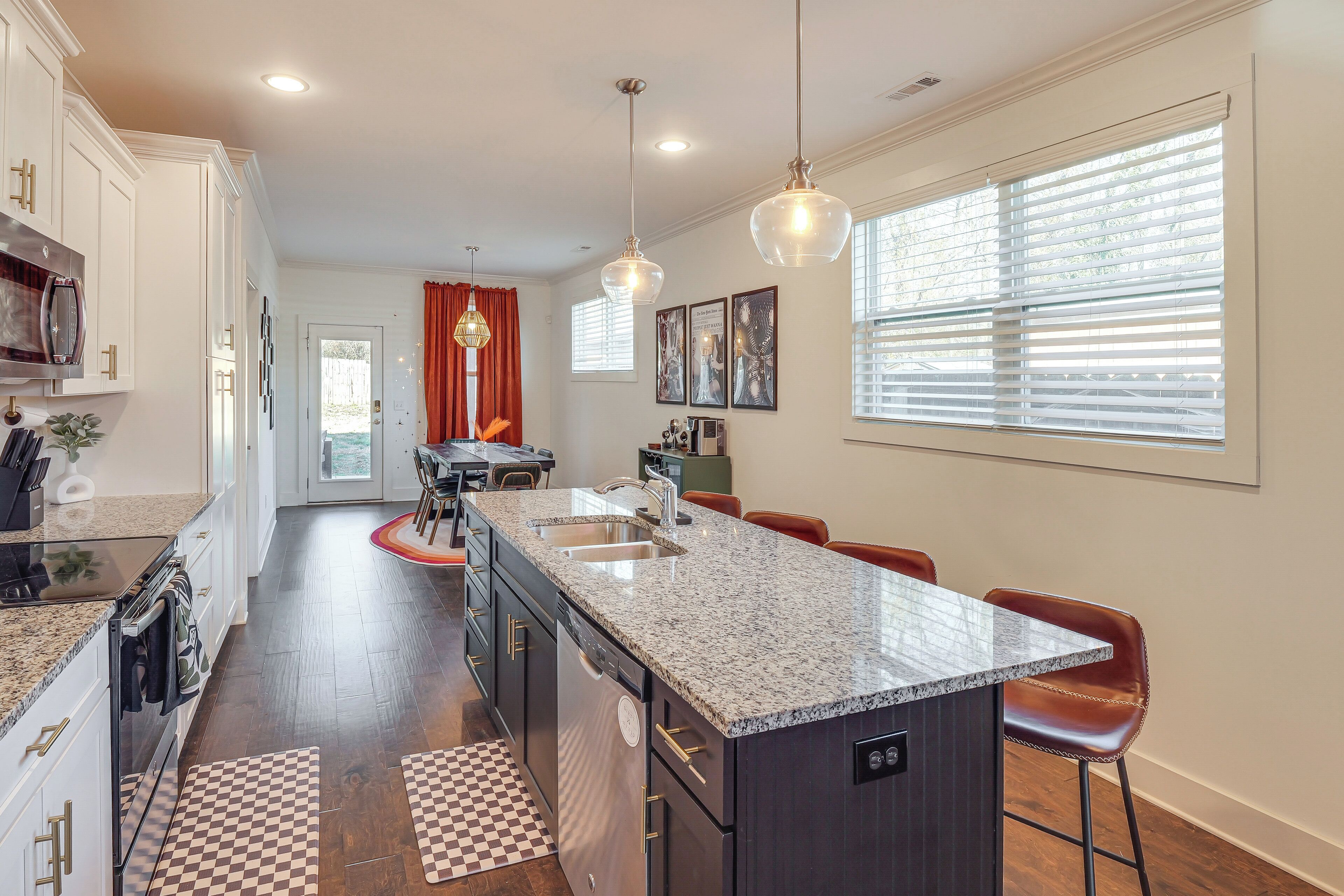 A modern kitchen with granite countertops, a central island, and bar stools.