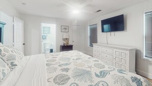 A bedroom with a bed, a TV, a ceiling fan, a dresser, and a window. - 3BR Coastal Home w/ Coastal Design- Steps to Sand (Galveston)