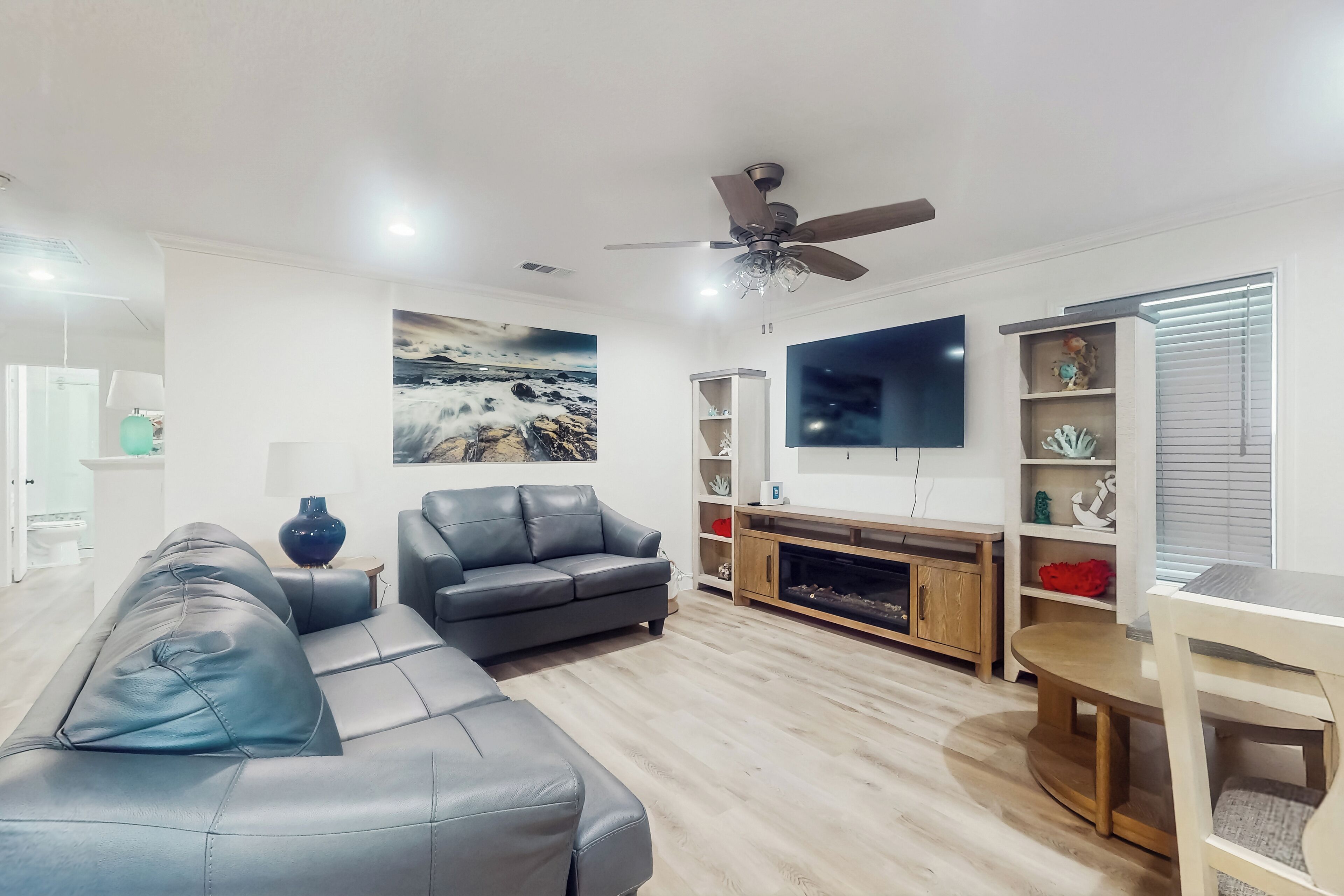 A modern living room with a sofa, TV, fireplace, and decorative shelves.