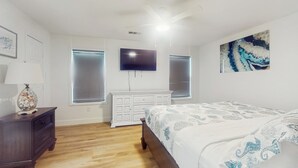 A bedroom with a bed, a dresser, a TV, and a painting on the wall. - 3BR Coastal Home w/ Coastal Design- Steps to Sand (Galveston)