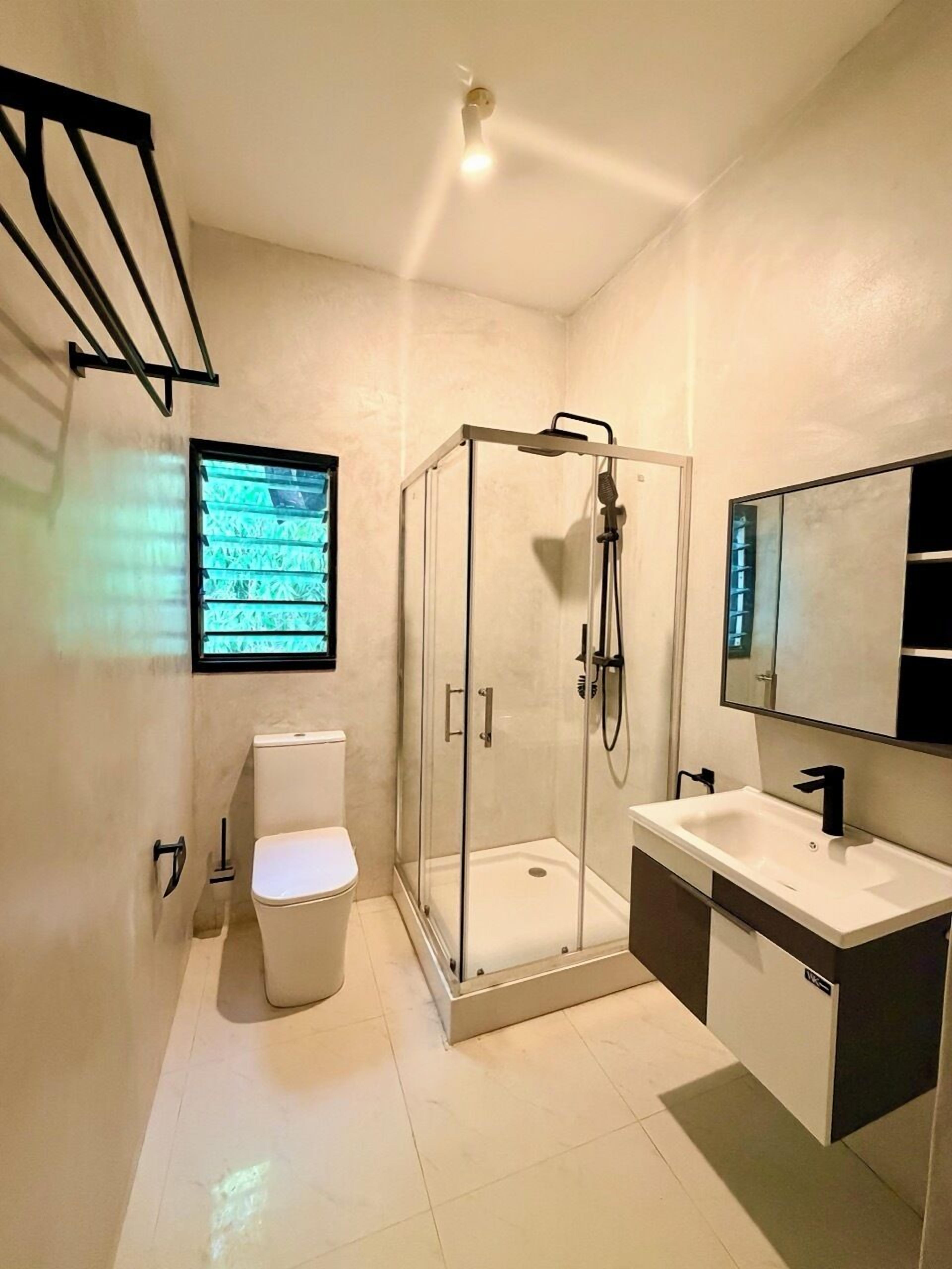 Een moderne badkamer met een douchecabine, toilet, wastafel en een grote spiegel.