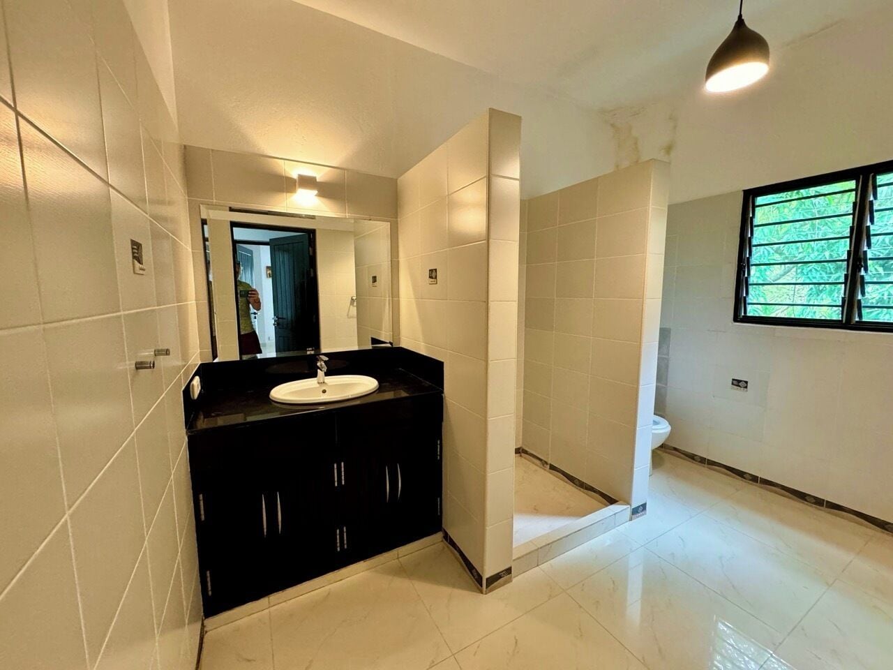 A bathroom with a black vanity, a white sink, and a large mirror.