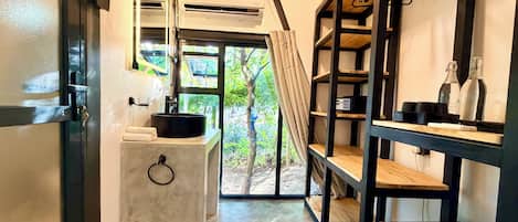 Un baño moderno con lavamanos, espejo y estanterías.