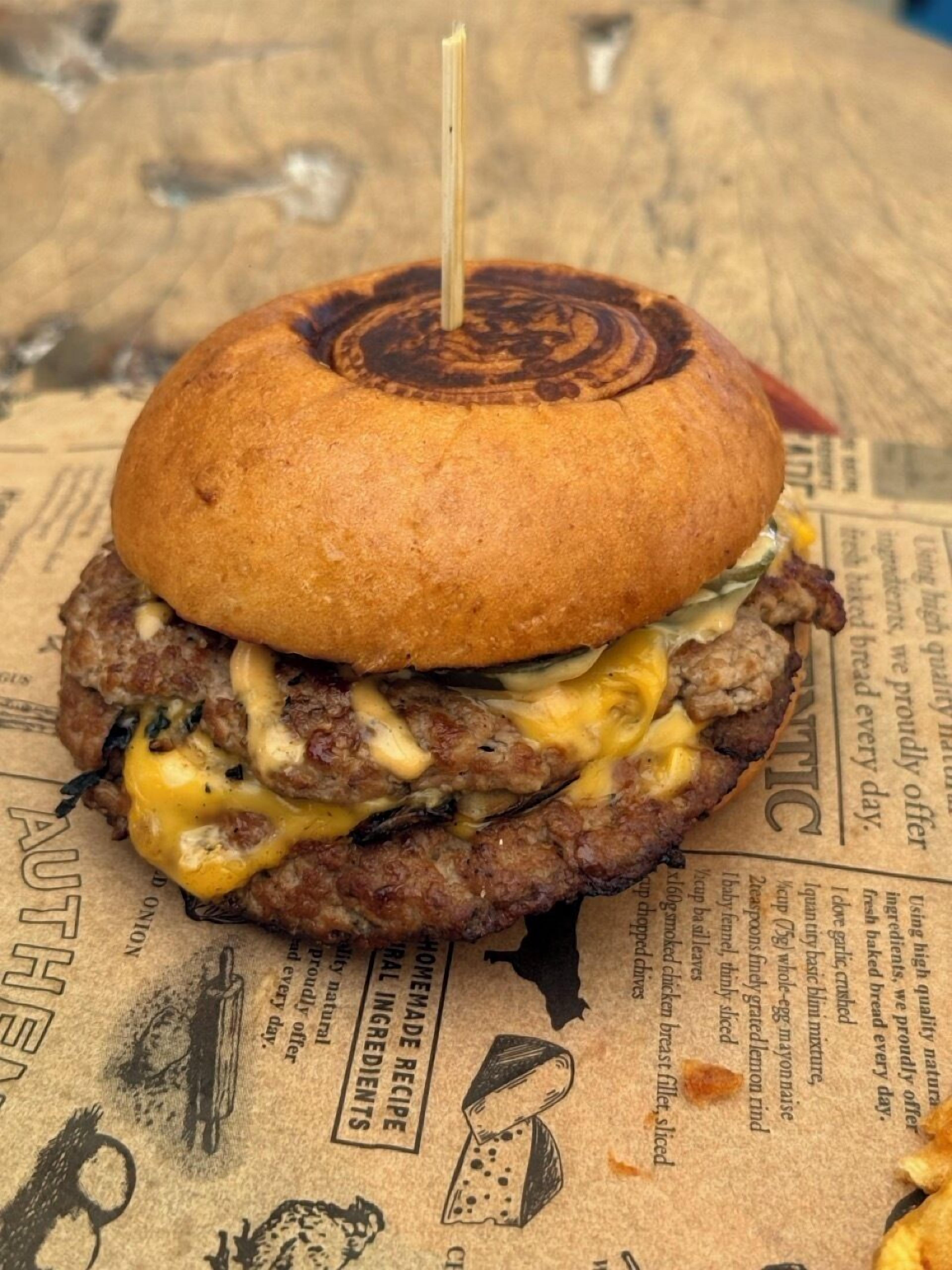 Ein Burger mit Zahnstocher, platziert auf einer Oberfläche mit Zeitung.