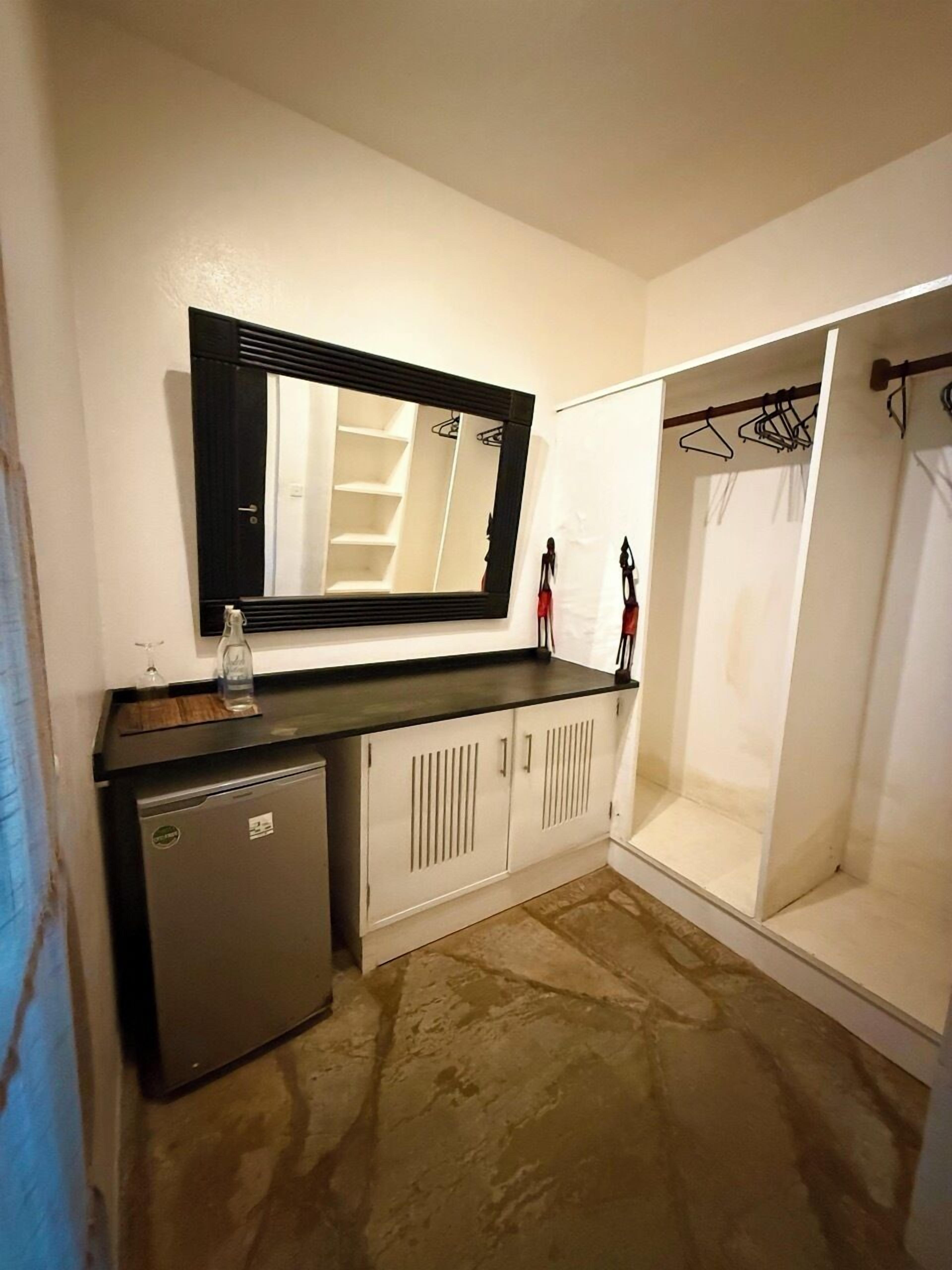 Un baño pequeño con espejo, lavamanos, armario y zona de ducha.