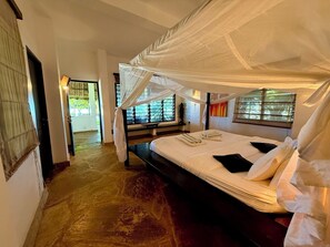 A room with a bed under a canopy, a bench, and a view through a window. - Galu Ecolodge (Diani Beach)