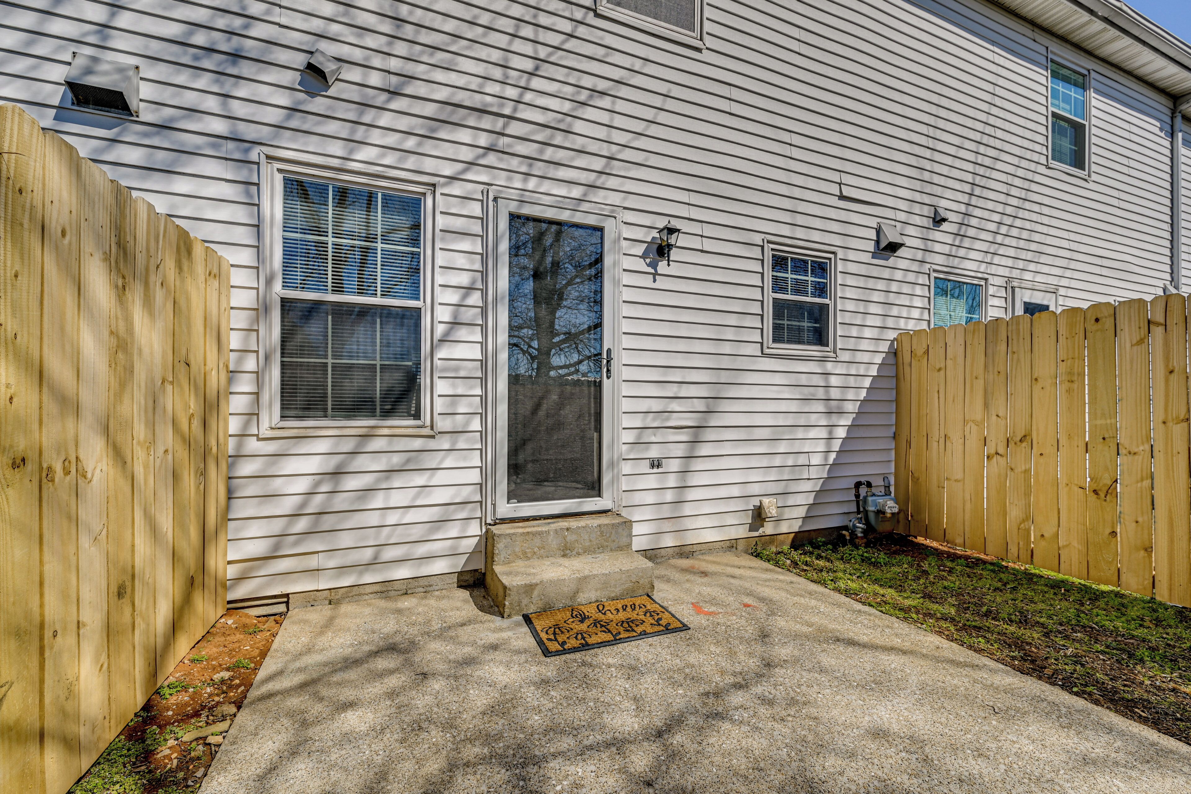 A house with a front door, a wooden fence, and a concrete driveway.