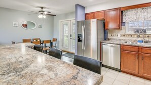 Eine Küche mit Granit-Arbeitsplatten, Holzschränken, einem Edelstahlkühlschrank und einem Geschirrspüler.