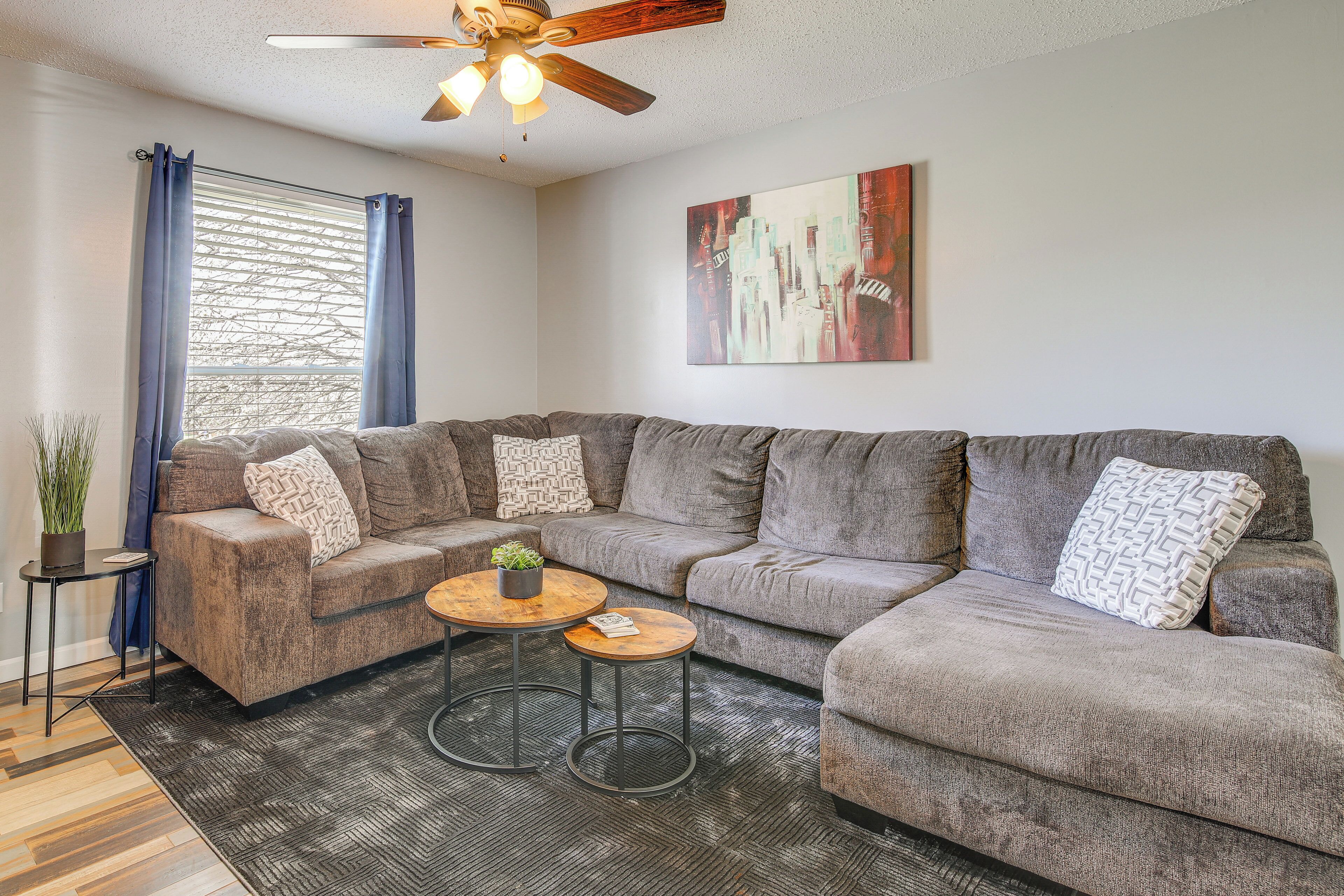 A modern living room with a sectional sofa, a small coffee table, and a ceiling fan.