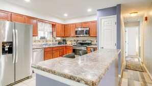 Eine moderne Küche mit Granit Arbeitsplatten, Edelstahlgeräten, Holzschränken und einer eingebauten Mikrowelle.