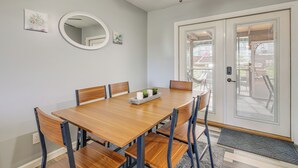 Ein Essbereich mit Holztisch, sechs Stühlen, Deckenventilator und einer Tür mit Blick ins Freie.