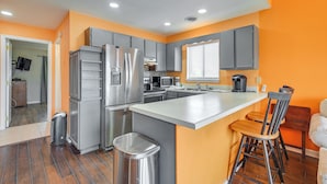 A modern kitchen with grey cabinets, stainless steel appliances, and a central island with bar stools. - Pool Access & Near Beach! Golf Colony Resort Condo (Surfside Beach)