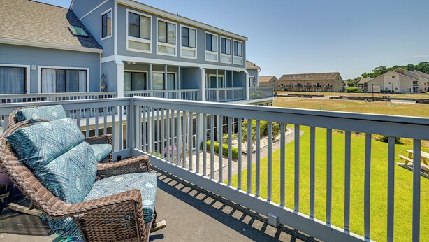 A balcony with wicker furniture and a view of a grassy area and buildings. - Pool Access & Near Beach! Golf Colony Resort Condo (Surfside Beach)