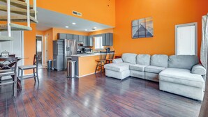 A modern living room with a gray sectional sofa, a dining area with a wooden table and chairs, and a kitchen with gray cabinets and stainless steel appliances. - Pool Access & Near Beach! Golf Colony Resort Condo (Surfside Beach)
