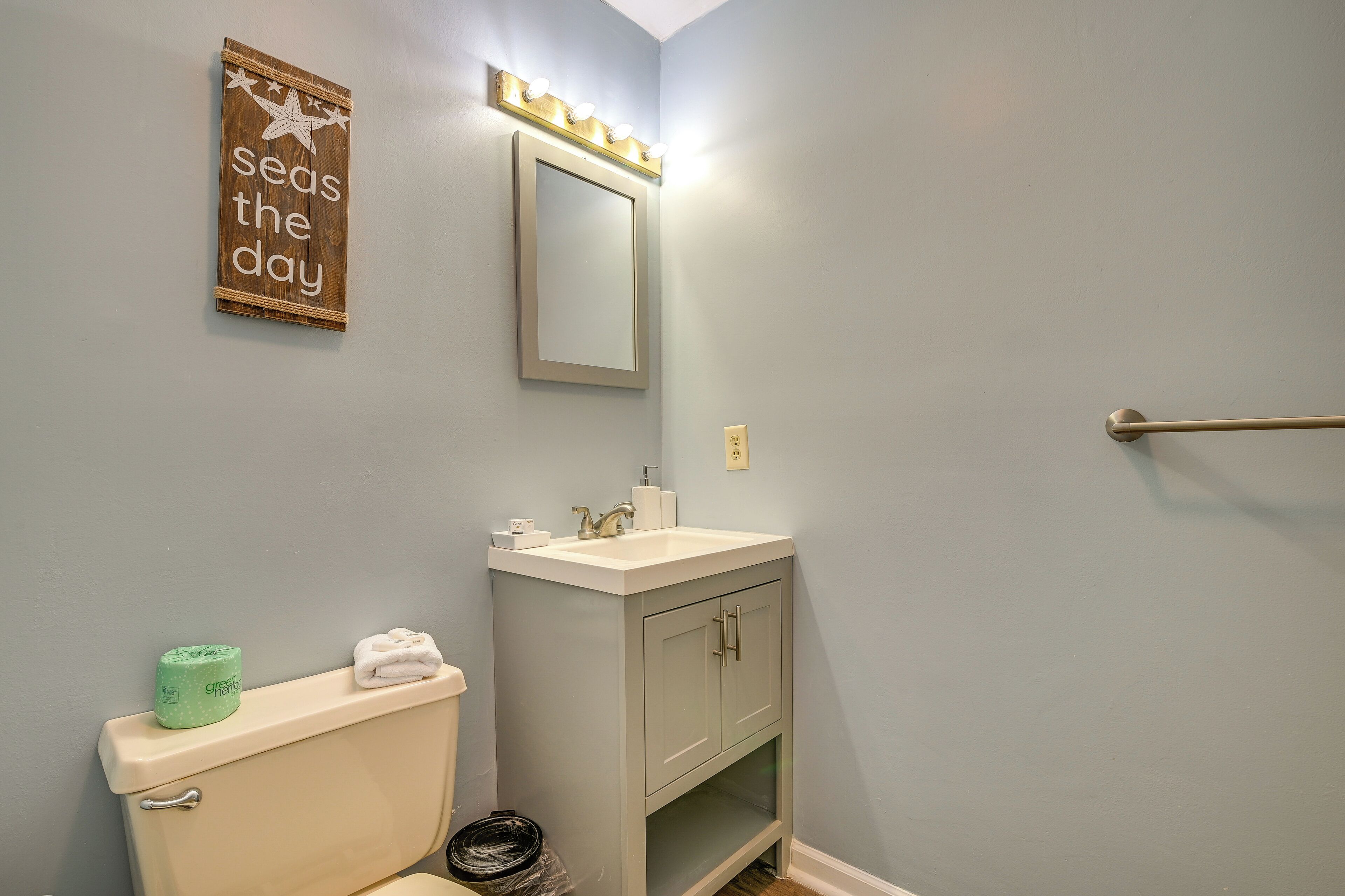 A bathroom with a toilet, sink, and mirror.