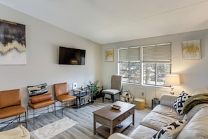 A modern living room with a sofa, chairs, a coffee table, and a TV.