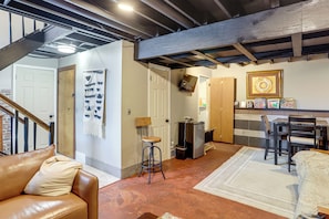 A spacious living area with a brown leather couch, a white rug, and a wooden dining table with chairs.