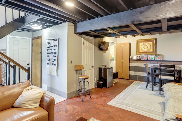 A spacious living area with a brown leather couch, a white rug, and a wooden dining table with chairs.