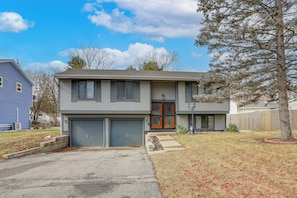 A two-story house with a garage, a front porch, and a small front yard.