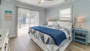 A bedroom with a bed, a nightstand, a ceiling fan, and a window with blinds. - < 1 Mi to Beach: Oak Island Retreat w/ Swim Spa! (Oak Island)