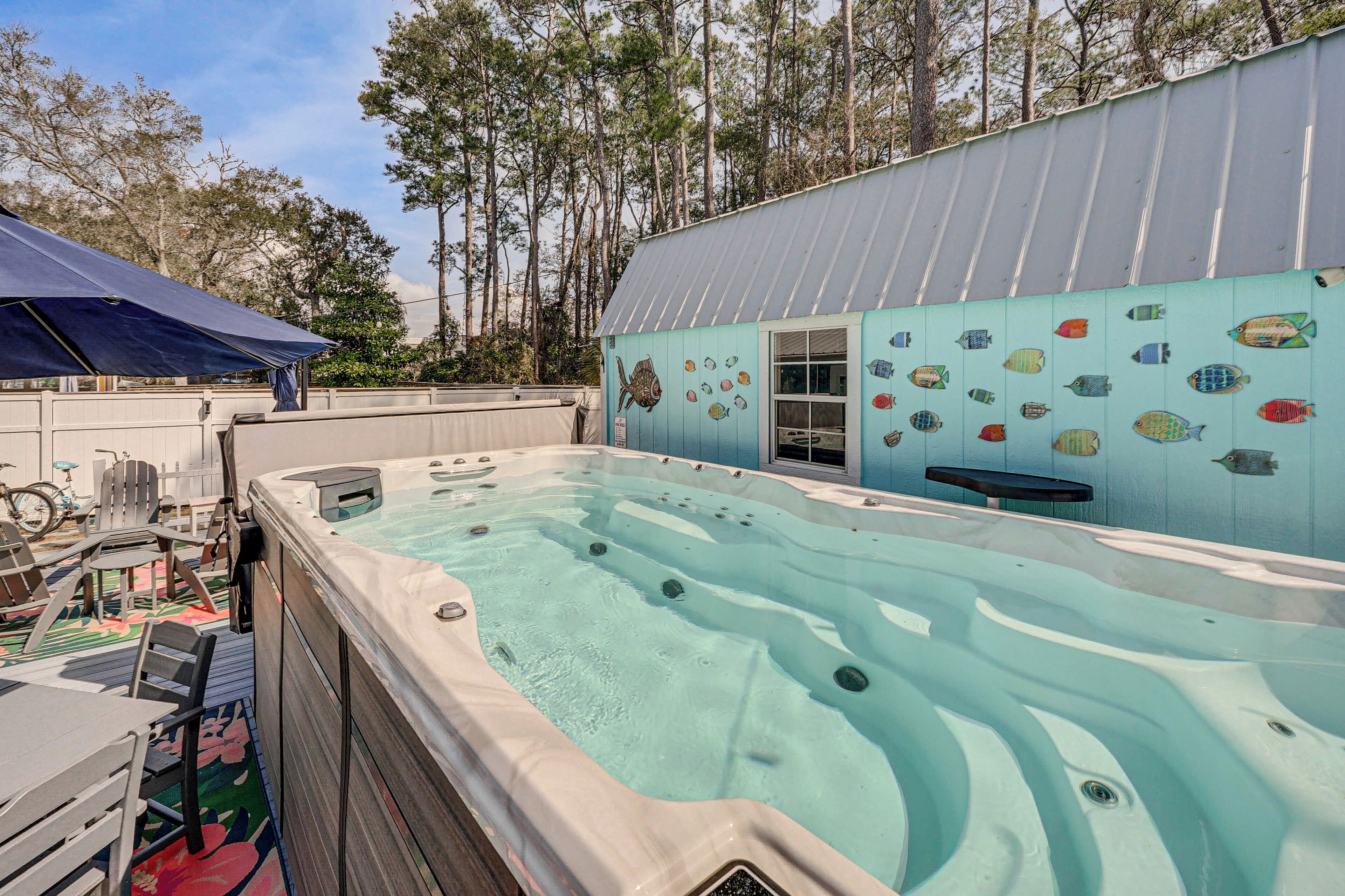 A hot tub area with a pool, surrounded by a building with fish murals, outdoor seating, and a covered patio.