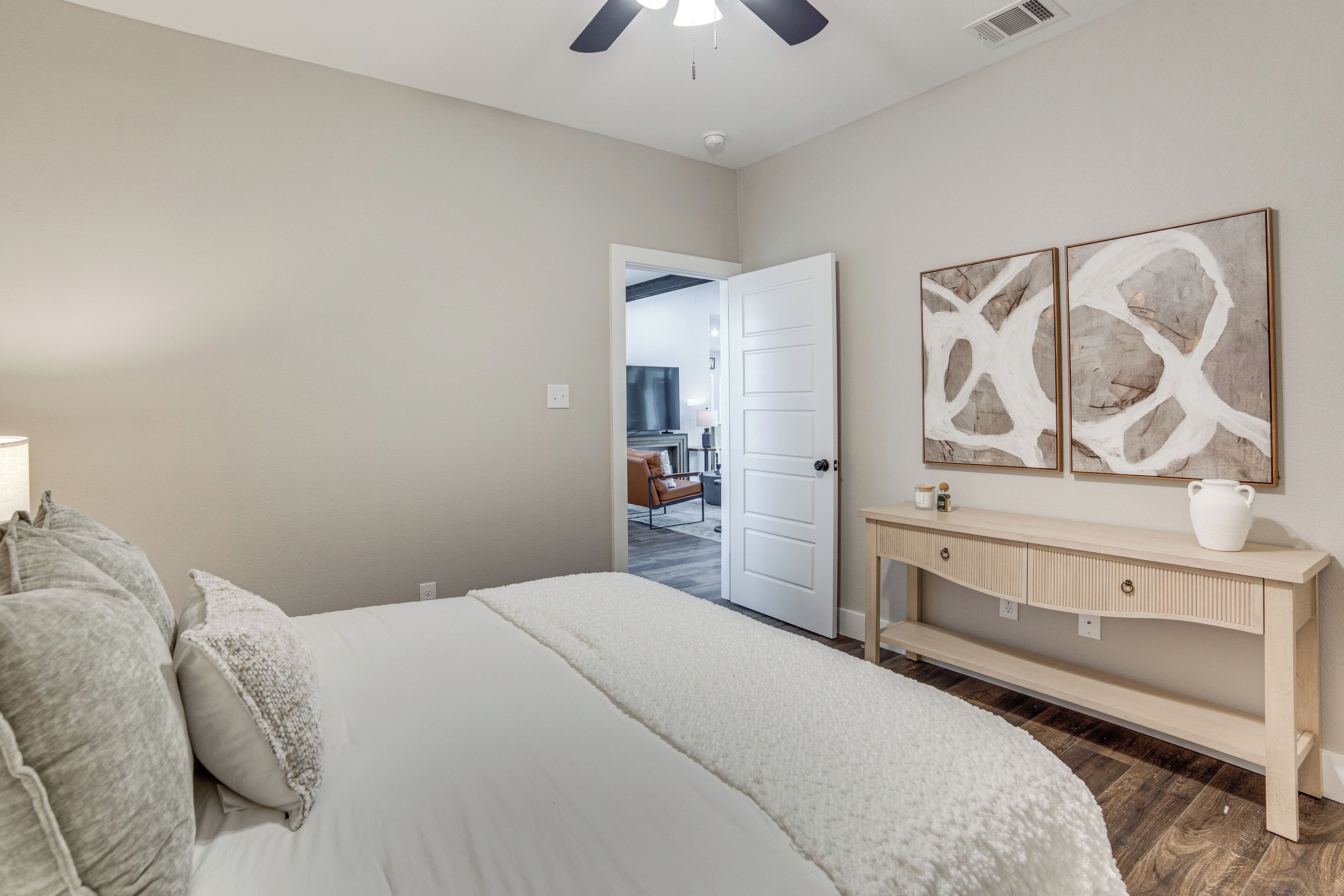 A bedroom with a bed, a console table, and abstract wall art.